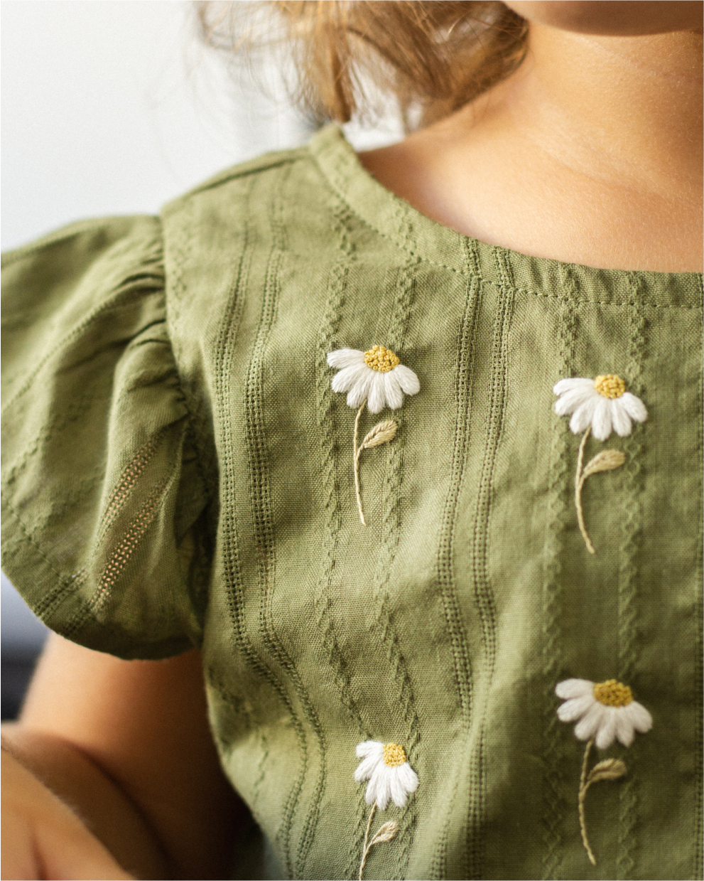 Vestido verde com margaridas bordadas à mão.