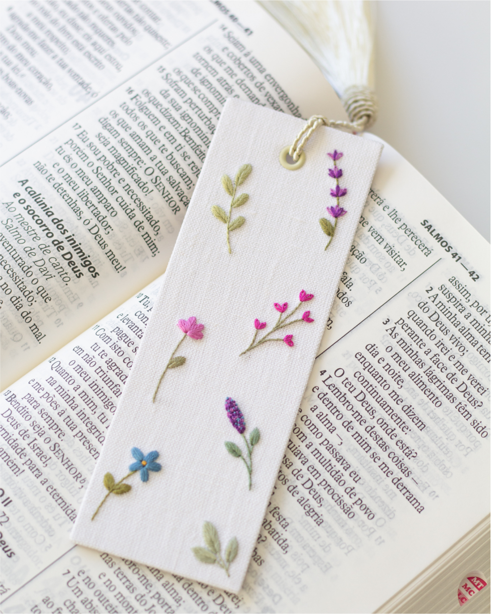 Marcador de tecido bordado com flores sobre uma Bíblia.